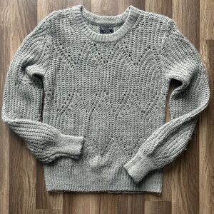 Gray sweater with a looser knit style. It is very soft and comfortable.
